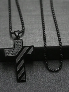 Vue macro d'un pendentif croix en acier noir avec gravures d'étoiles et de rayures