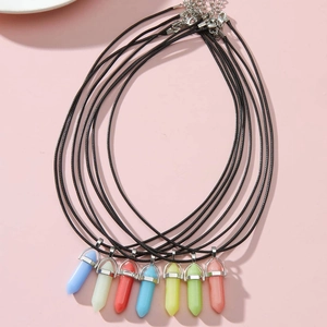 Détail de pendentifs hexagonaux multicolores avec cordons noirs sur fond rose