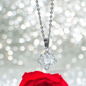 Collier flocon de neige avec zircon et perle sur un fond de roses rouges