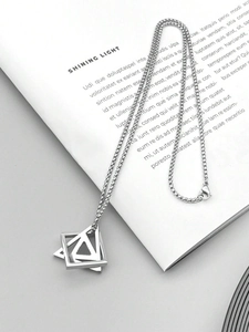 Detailed view of silver geometric layered triangle and square pendant on a magazine
