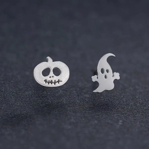 Detail of silver pumpkin and ghost stud earrings for Halloween on a dark surface