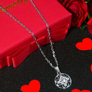 Silver flower pendant necklace with crystals displayed on a red gift box with roses
