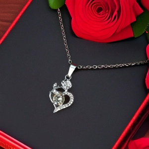Silver heart pendant necklace with rhinestones and red rose gift box background