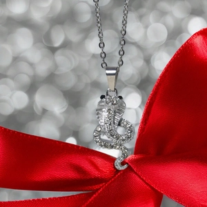 Collana con ciondolo a cobra argentato con cristalli scintillanti su sfondo di nastro rosso