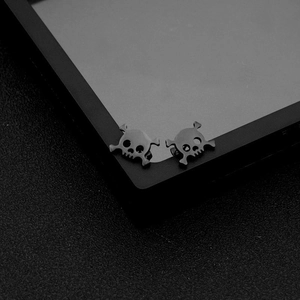 Macro shot of matte black stainless steel skull stud earrings with a punk gothic design