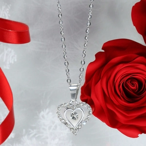 Collier double cœur avec strass et chaîne en argent sur un fond de rose cadeau