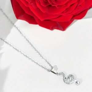 Collier note de musique clé de sol argenté avec cristaux sur fond blanc