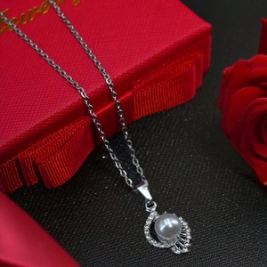 Elegant white pearl necklace with diamond-encrusted pendant on red silk rose gift box