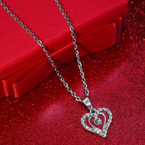 Collier double cœur argenté avec strass sur fond de boîte cadeau rouge élégante