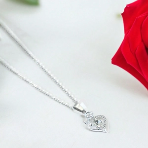 Close-up of rose heart pendant necklace with shimmering crystals and a red rose accent