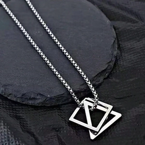 Minimalist silver geometric double triangle pendant necklace on a dark rock texture