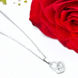 Dettaglio della collana con ciondolo a doppio cuore e cristalli con rosa rossa