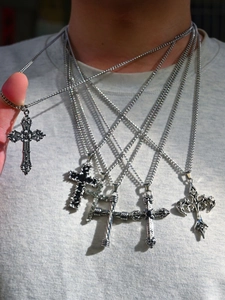 Detail of layered silver cross pendants with gothic, embossed, and twisted textures