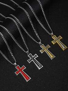 Détail de quatre colliers à pendentif croix bicolores sur un fond de cuir noir