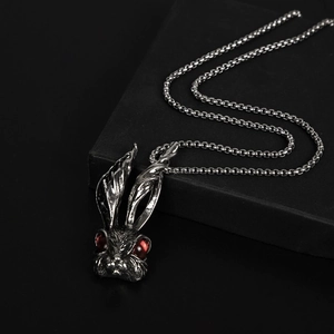 Retro titanium steel bunny pendant with red gemstone eyes on a minimalist black base