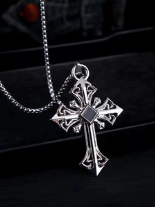 Macro detail of Gothic silver cross pendant with black gemstone and filigree engraving