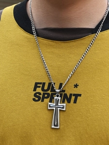 Détail du pendentif croix argentée avec émail noir sur une chaîne gourmette pour homme