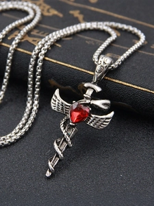 Macro shot of gothic sword pendant with heart-shaped red gem on vintage black book