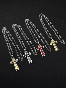 Vue détaillée de pendentifs croix bicolores superposés en or, noir et rouge poli