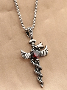 Macro detail of gothic sword pendant with red heart gemstone and coiled snake texture