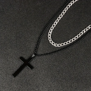 Detail of layered double-layer cross pendant necklace with silver Cuban chain and black cross