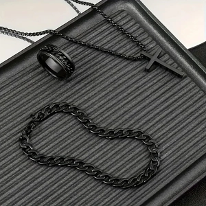 Macro shot of black stainless steel jewelry set with cross necklace, ring, and cuban bracelet