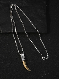 Détail du pendentif dent de loup vintage avec capuchon gravé et chaîne à boîte
