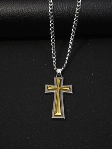 Détail du pendentif croix bicolore avec insert doré et cadre argenté sur fond texturé