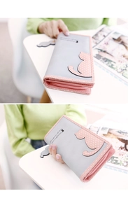 Detail of grey and pink long wallet with cat motif and zipper closure in hand