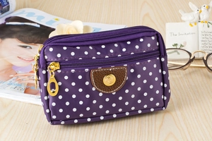 Detail of purple polka dot canvas wallet with three zipper pockets and leather accent