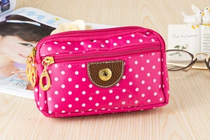 Detailed view of magenta polka dot canvas phone pouch with three zipper compartments