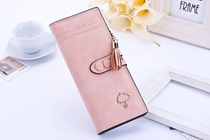 Gros plan sur un long portefeuille rose avec texture mate, pompon et logo de parapluie