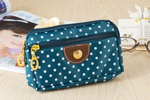 Detail of blue polka dot canvas phone bag with multiple zipper layers and golden hardware