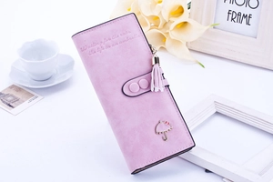 Détail d'un long portefeuille rose avec pendentif parapluie en métal et texture cuir mat doux