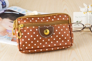 Close-up of brown polka dot canvas bag with three zippers and golden heart buckle