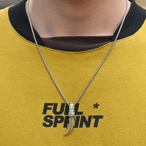 Collier vintage avec pendentif dent de loup pour couples sur fond de sweat-shirt jaune