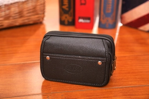 Detail of black pebbled leather waist bag with double zippers and metal rivets