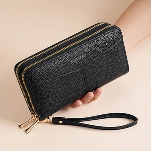 Detail of black double zipper clutch wallet in pebbled leather held by hand