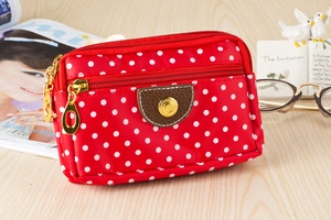 Close-up of a red polka dot canvas phone pouch with three zipper compartments