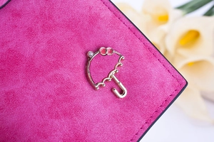 Détail du portefeuille en daim rose avec fermoir parapluie doré orné d'un strass