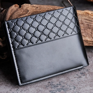 Close-up of black leather bifold wallet with geometric monogram embossing on wood background