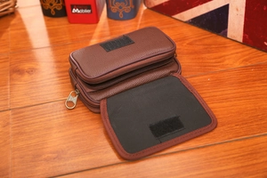 Macro detail of dark brown pebble leather belt pouch with dual zippers and velcro flap