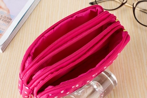 Detailed top view of pink polka dot canvas bag with three separate zipper pockets