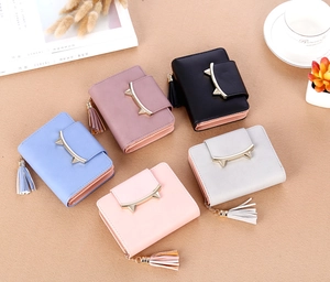 Flat lay of small tassel wallets in multiple colors with cat ear buckles and accessories