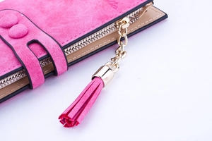Détail de portefeuille rose mat avec fermeture éclair dorée et pendentif à pompon