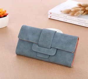 Blue long wallet for women with pebbled texture and layered decorative straps on a desk