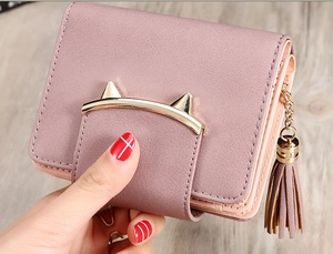 Close-up of pink leather wallet featuring golden cat-ear clasp and tassel detail
