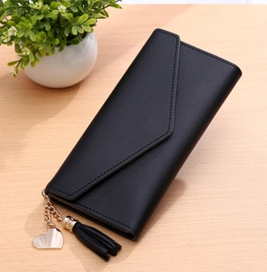 Detailed view of black envelope wallet featuring a gold heart pendant and long tassel charm