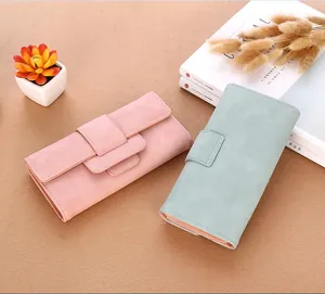 Detail view of pink and mint green long wallets with matte texture and buckle closure