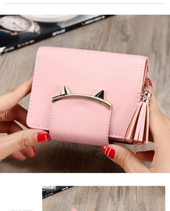 Detail of pink PU leather purse with gold cat ear clasp and tassel held by hand